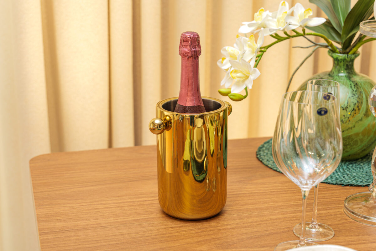 Balde dourado com espumante ao lado de vaso com orquídeas brancas