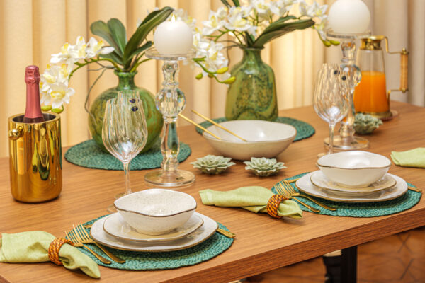 Mesa posta sofisticada com louça off-white e sousplat verde natural